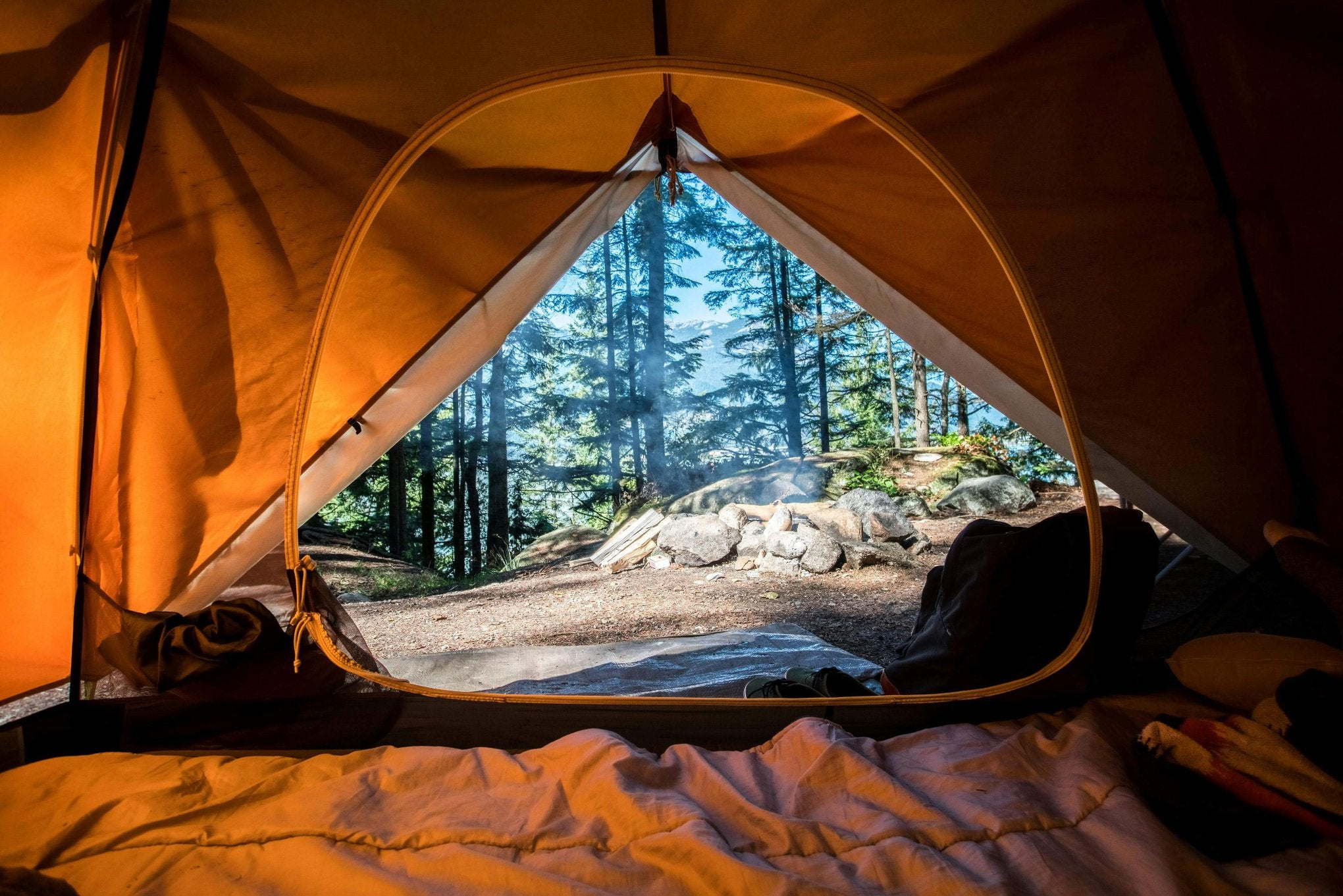 outdoor campsite view from inside a tent in the woods 